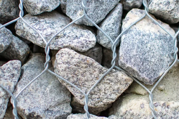 Gabion vägg närbild. Texturerad bakgrund. Gabion är stenar i trådnät som används för erosionskontroll. — Stockfoto