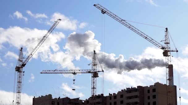 Construção em casa, guindastes de construção no fundo da planta, a fumaça das chaminés, construção, poluição ambiental — Vídeo de Stock