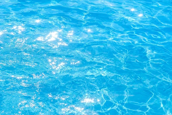 Oberfläche des blauen Schwimmbeckens, Hintergrund des Wassers im Schwimmbecken. Textur, blaues Wasser, helle Sonnenstrahlen — Stockfoto