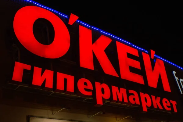 Tyumen, Rusia - 03 de octubre de 2019: supermercado OKAY en de la ciudad. Red minorista de hipermercados que vende productos alimenticios en Rusia. signo de noche logo — Foto de Stock