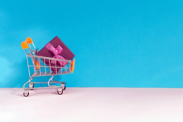 Winkelwagen volledige collectie van winkeltijd. e-commerce, cadeautjes kopen. op een blauwe, roze achtergrond. — Stockfoto