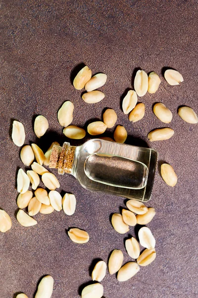 Peanut oil on a brown background close-up. selective focus. the use of oil in cooking, dietetics, cosmetology, an excellent component for products designed for skin care. top view flat lay, vertical p