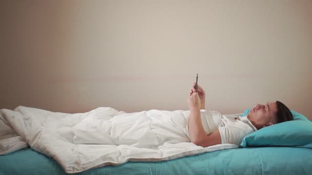 Go to bed a young man sets an alarm on his mobile phone to get ready for bed. — Stock Video