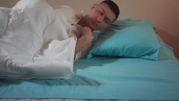 Junger Kerl, der sich bereit macht, auf dem Bett aus nächster Nähe zu schlafen. Gesunder Schlaf — Stockvideo