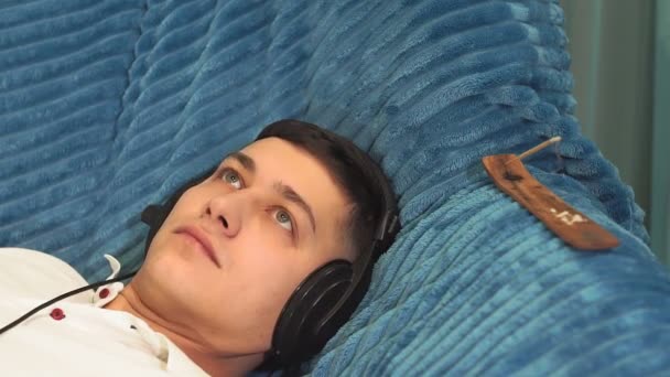 Młody opalony mężczyzna zbliżenie w białym t-shirt w domu słuchając relaksującej muzyki. relaks, relaks, spokój — Wideo stockowe