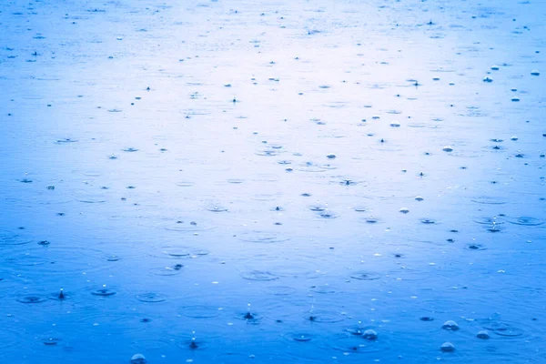 Легкий дождь на поверхности речной воды делает круговые узоры. Текстура и поверхность воды в реке. — стоковое фото