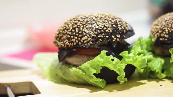 Hamburger. Gros plan d'un délicieux hamburger de pain noir, de côtelette de bœuf ou de porc . — Video