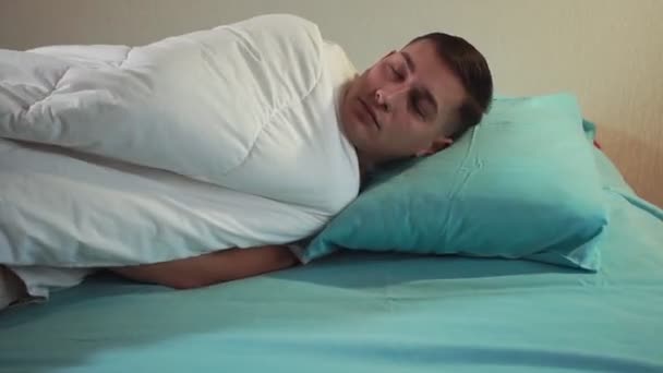 Молодой человек ложится спать на кровать. селективный фокус, здоровый сон — стоковое видео