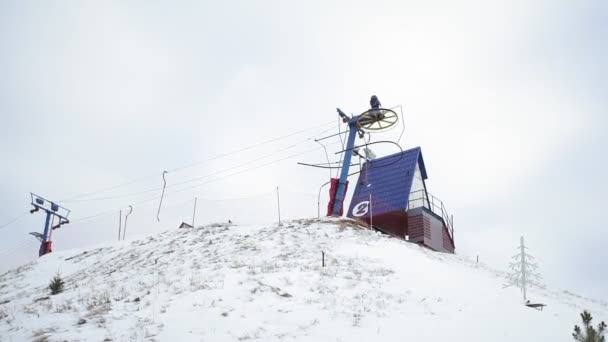 Estación de esquí y en T-bar telesilla en la pista, de mano. Ciudad bajo la nieve, esquiadores utilizando elevación de superficie en invierno. Subiendo a la colina usando telesilla. Invierno — Vídeos de Stock