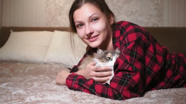 猫ペットを撫でるベッドの上に横になった少女の肖像画。本物のビデオ友情愛家庭の快適さ — ストック動画