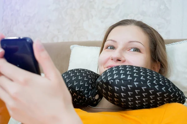 Young girl in the bedroom looks at the phone close-up smiling laughing browsing social networks. — Stock Photo, Image