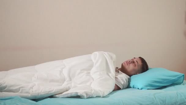 Genç adam yatağa girer, rahat bir yatakta uyuyakalır. Uyuyan adam. — Stok video