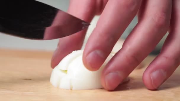Man Cutting Boiled Egg on Chopping Board With Knife. eggs for the salad, close-up