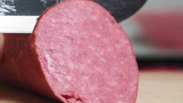 Couper la saucisse fumée avec un couteau. Les tranches de saucisse reposent sur un plan rapproché de la planche à découper. Cuire les tranches de viande — Video