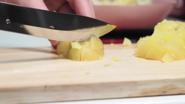 Pellkartoffeln schneiden. Hände schneiden gekochte Kartoffeln mit einem großen Messer auf einem hölzernen Schneidebrett. Hausmannskost, Salatzutat — Stockvideo