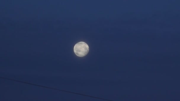 Luna llena contra un cielo azul oscuro — Vídeos de Stock