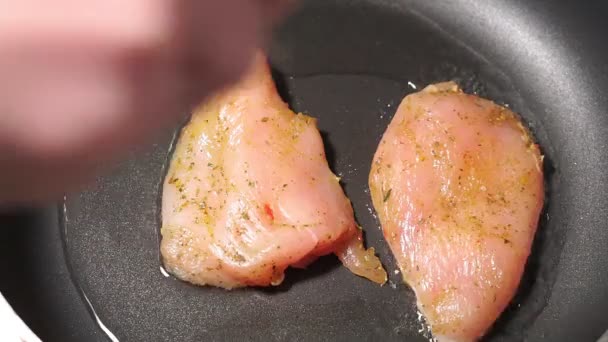 Pedaços crus de filé de frango são colocados em uma panela quente e fritos — Vídeo de Stock