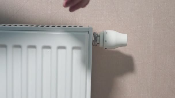 Rotating white temperature valve with hand on wall mounted heating water radiator — 图库视频影像
