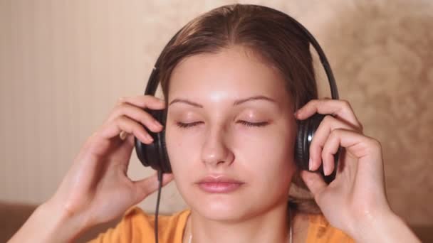 Портрет молодой девушки, слушающей музыку дома. глядя в камеру — стоковое видео