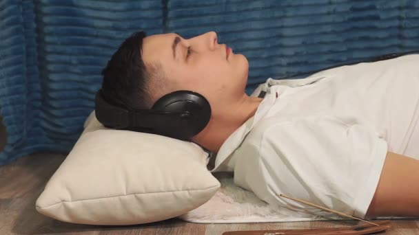Молодий чоловік слухає тиху музику з навушниками. розслаблення — стокове відео