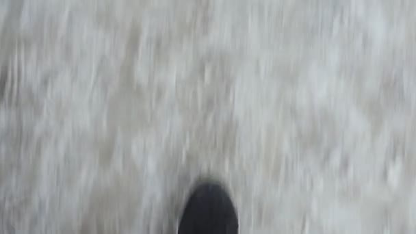 Человек в черных кроссовках идет по грунтовой дороге. плохая погода, снег тает — стоковое видео