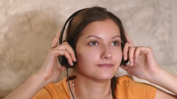 Ung flicka närbild lyssna på musik med hörlurar, hemma. — Stockvideo