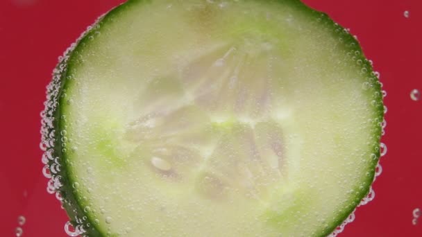 Φυσαλίδες και μια σταγόνα νερό στο πλάι ενός ποτηριού με φέτες αγγουριού και πάγο. για να κλείσει. μακροσκοπική επιλεκτική εστίαση νωπών λαχανικών — Αρχείο Βίντεο