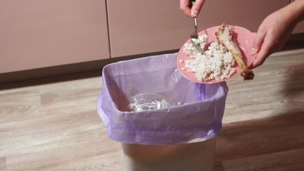 Throws food in the trash. uneaten food from a plate in the trash bin. Throwing away meal — Stock Video