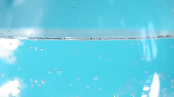 Blue liquid water soda in a glass glass close-up bubbles. selective focus, background — 비디오