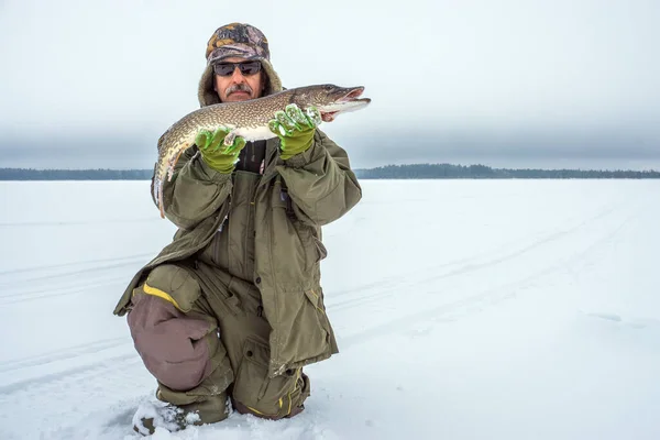 寒い曇りの日に冬の釣りに成功した男は冷凍魚を持っている 冬のスポーツフィッシング — ストック写真