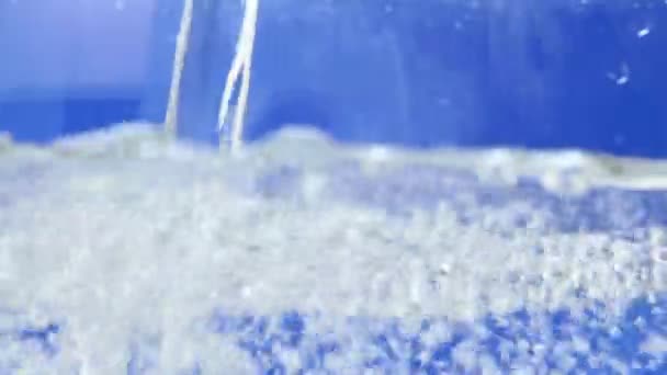 Verse du liquide dans un verre, de l'eau en gros plan macro. focus sélectif — Video