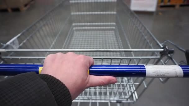 El hombre en un supermercado está pasando por la canasta más allá de los mostradores. compras en un hipermercado — Vídeo de stock