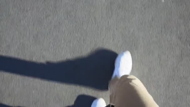 POV disparo de un hombre pies caminando en la acera con zapatillas blancas a plena luz del día — Vídeos de Stock