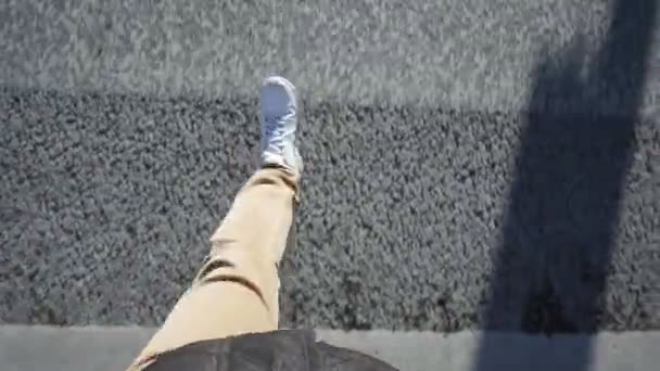 Hombre camina sobre el asfalto en zapatillas blancas, cruza la carretera en un cruce peatonal — Vídeo de stock