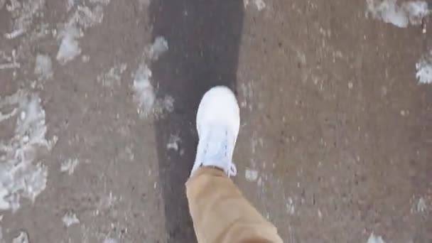 Witte sneakers wandelingen op nat asfalt stoep in de sneeuw POV video — Stockvideo