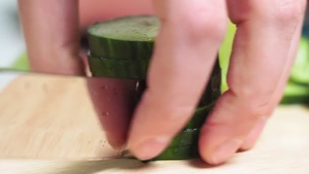 Los trozos de los pepinos en el primer plano. la tabla de cortar de madera. mens manos cortadas con un cuchillo de cocina, cocinar verduras frescas — Vídeo de stock