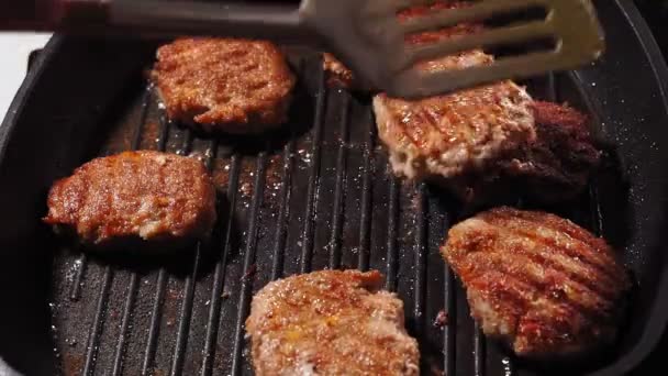 Schnitzel in Großaufnahme auf einer Grillpfanne braten. Spachtel dreht sich, kocht hausgemachte Burger — Stockvideo