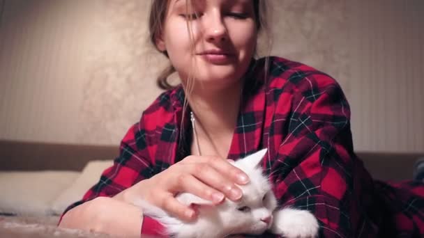 Молода дівчина погладжує пухнастого кота, що лежить на дивані. вибірковий фокус. Домашні тварини — стокове відео
