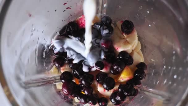 Healthy food concept. making milkshake with fruits and berries bananas, smoothies. Pouring the milk into the fruit, selective focus — Stock Video