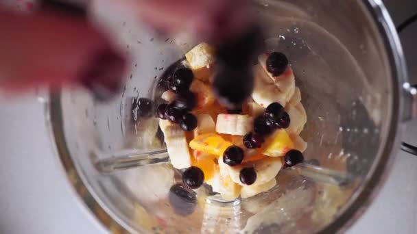 Gyümölcsből és bogyóból turmixot készítek. Gyümölcskeverékkel működő turmixgép. Egészséges étrend élelmiszer, banán, bogyók szelektív fókusz — Stock videók