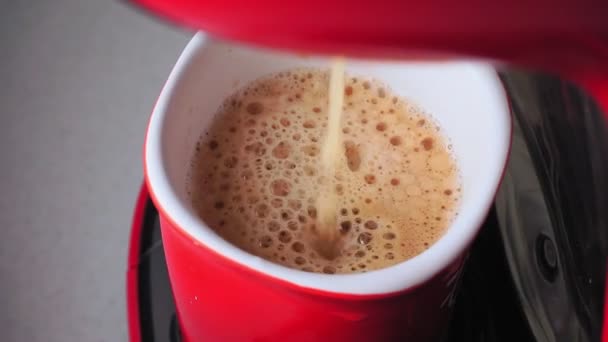 Kaffee aus der Kaffeemaschine wird aus nächster Nähe in einen Becher gegossen — Stockvideo