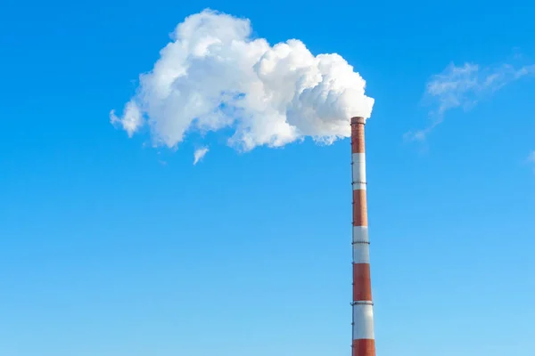 Pipe with white smoke against the background of blue sky and copy space. emission of steam and smoke into the atmosphere