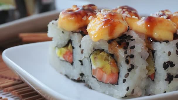 Sushi na białym talerzu z bliska, makro awokado, ser śmietankowy, sezam. Japońskie menu restauracji — Wideo stockowe