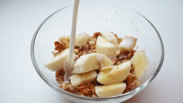 Vierte la leche en la granola con plátanos de cerca. dieta saludable Desayuno — Vídeo de stock