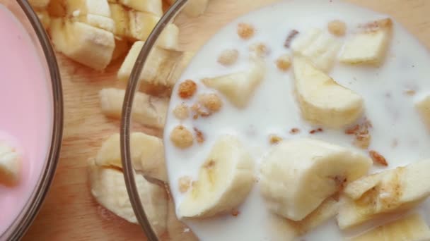 Muesli avec yaourt au lait et banane en assiettes close-up focus sélectif . — Video