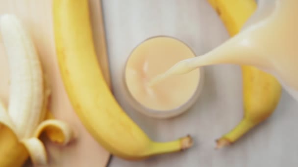 バナナスムージー、バナナジュースが注ぐ、ガラスに選択的な焦点 — ストック動画