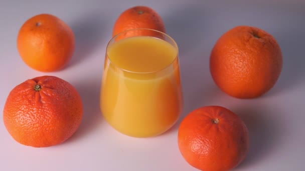 Glass of orange juice and oranges fruit on a white background, selective focus — Stock Video