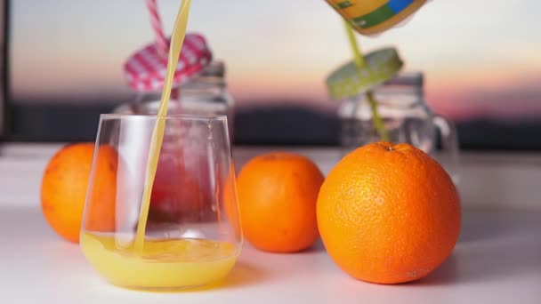 Glass of orange pours juice and oranges fruit on a white background. — Stock Video