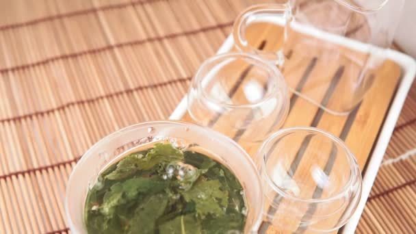 Warme groene thee wordt in de glazen kom gegoten. Close-up — Stockvideo