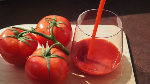 Succo di pomodoro saporito in un bicchiere con pomodori rossi maturi . — Video Stock